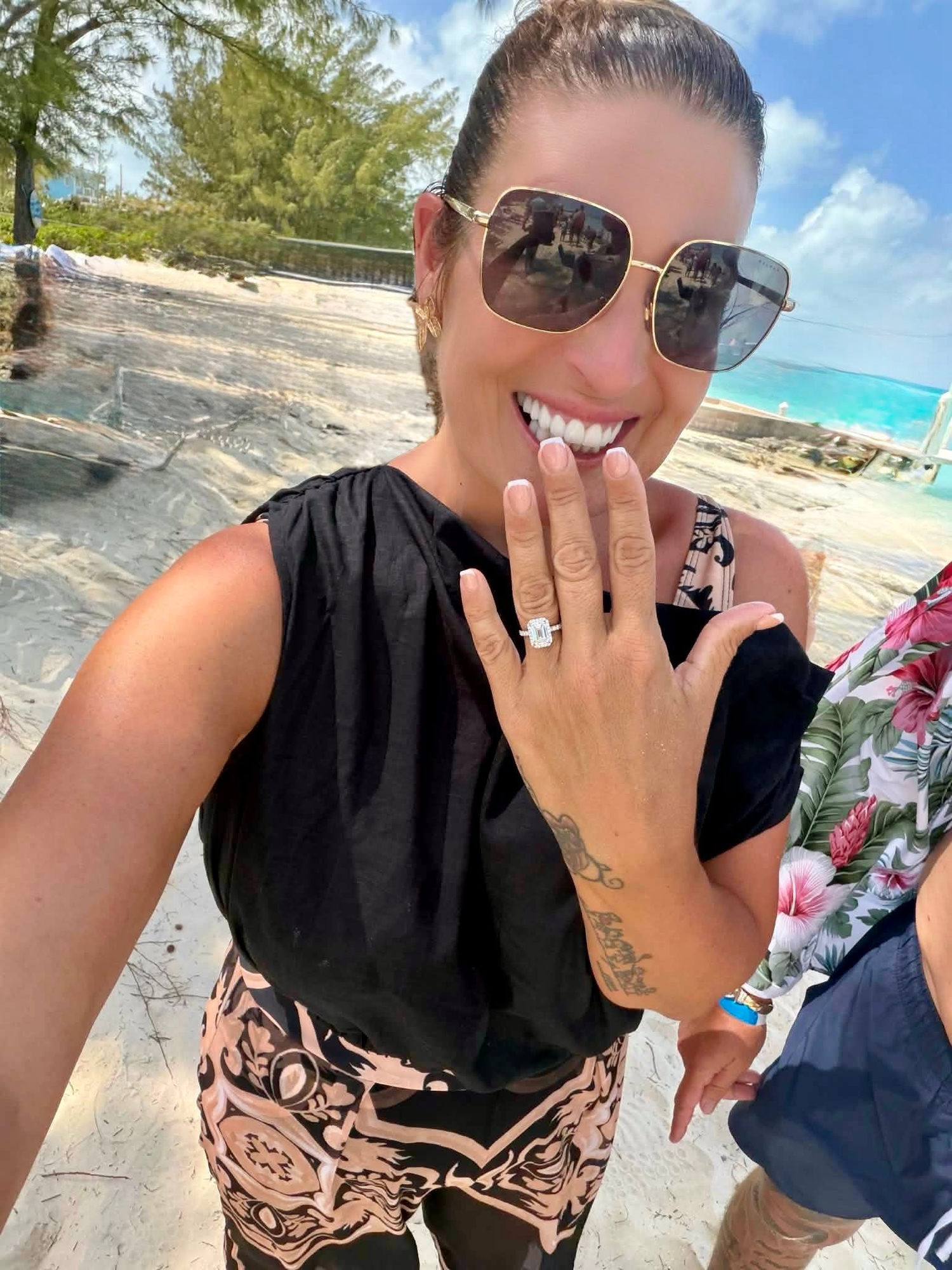 Katie laughing on the beach, showing off her engagement ring