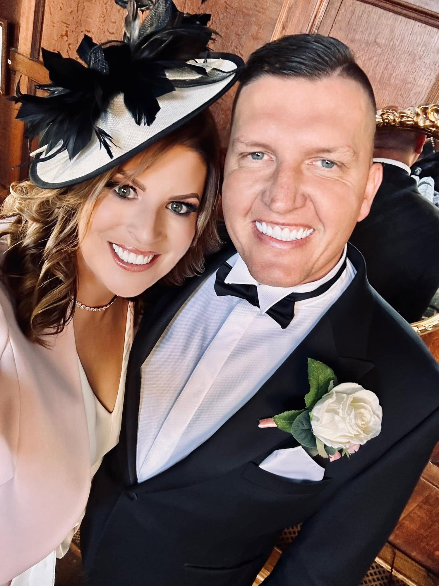 Katie and Matt dressed up — Matt in a tuxedo, Katie in a feathered fascinator