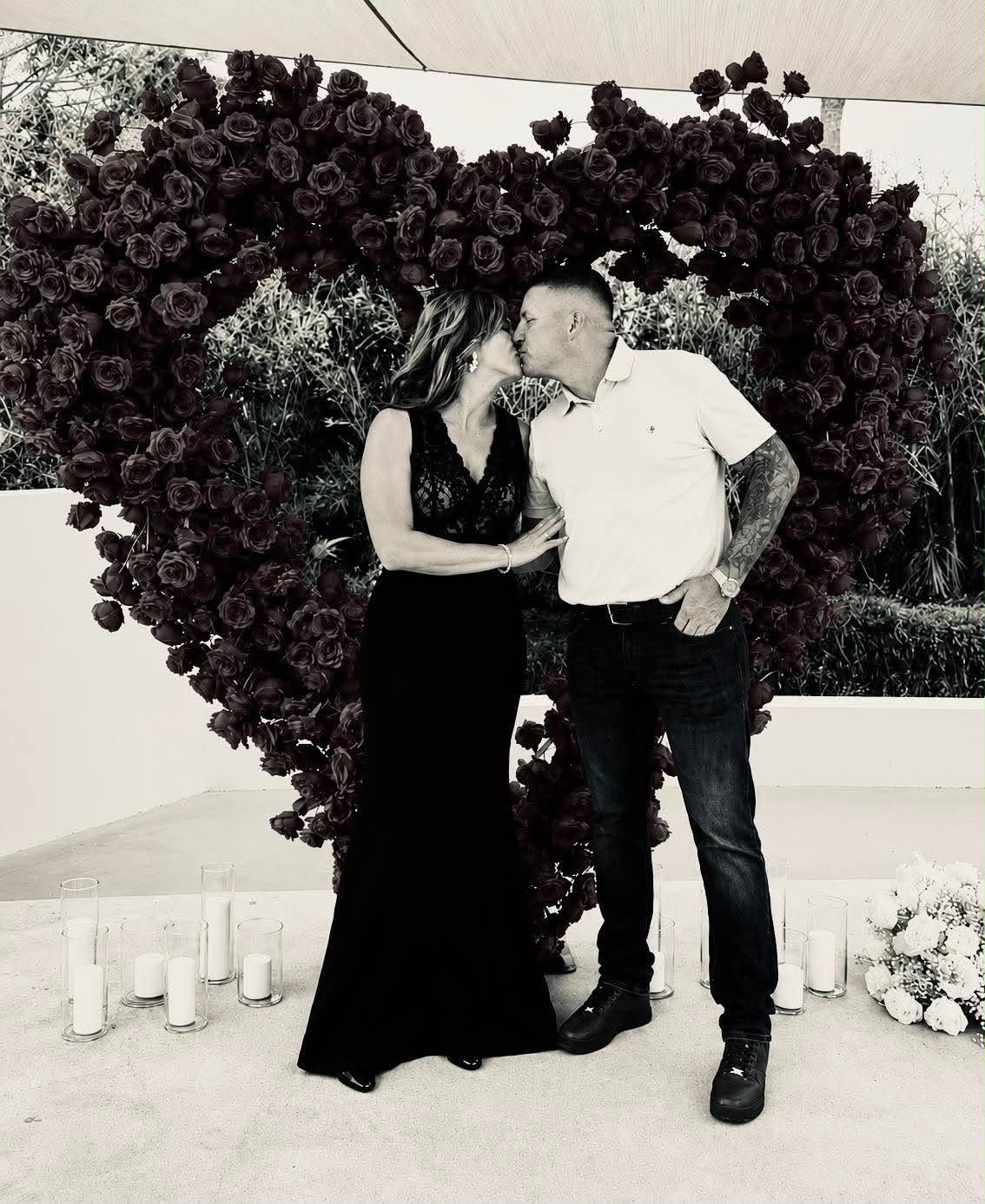 Katie and Matt sharing a kiss in front of a rose-heart arch