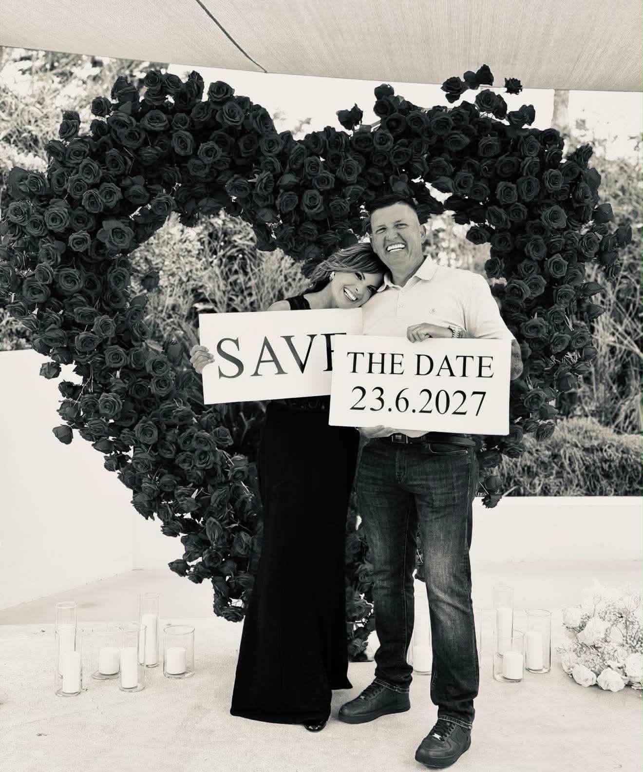 Katie and Matt holding a Save the Date 23.6.2027 sign