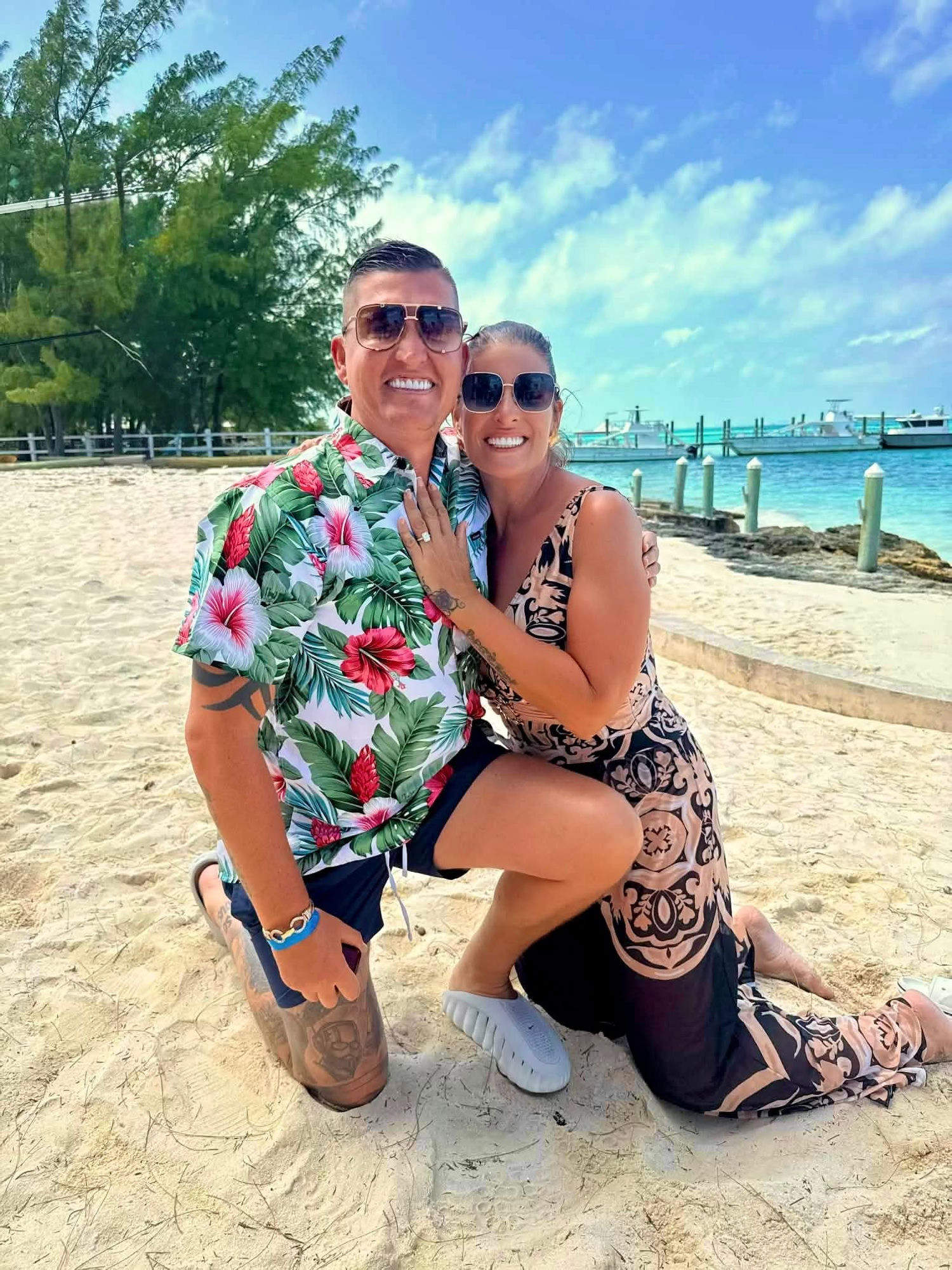 Katie and Matt embracing on the sand just after the proposal